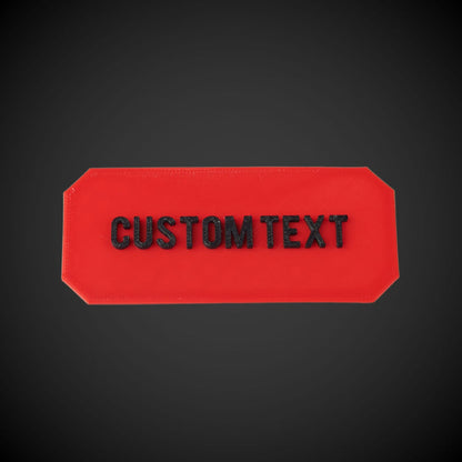 Red rectangular plate with 'CUSTOM TEXT' on a black background