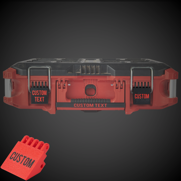 Red and black tool battery pack with 'CUSTOM TEXT' labels and latches on a dark background