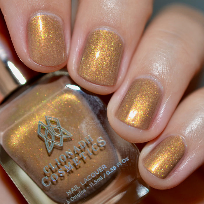 Close-up of nails painted with Lattes and Ciders Nail Lacquer on fair skin tone. Hand is holding polish bottle.