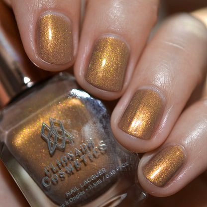 Close-up of nails painted with Lattes and Ciders Nail Lacquer on fair skin tone. Hand is holding polish bottle.