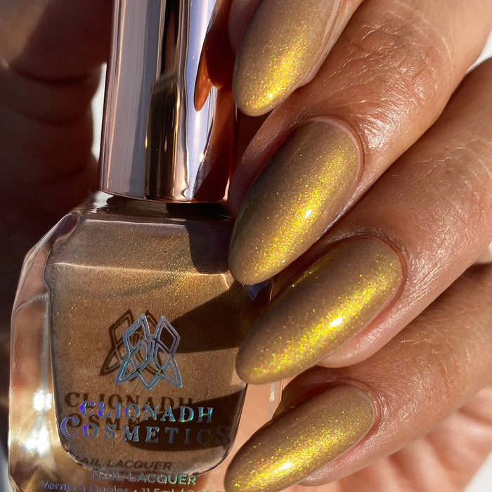 Close-up of nails painted with Lattes and Ciders Nail Lacquer on medium skin tone. Hand is holding polish bottle.