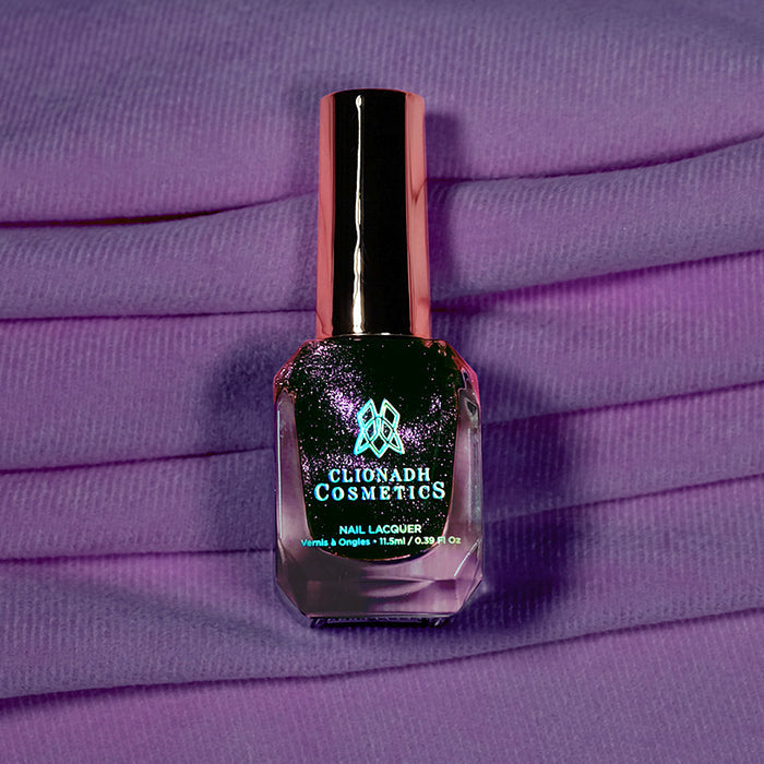 Bottle of nail polish containing Lilac Velour on a purple fabric background.