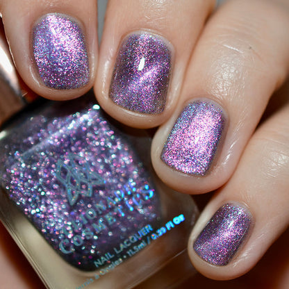 Close-up of nails painted with Lilac Velour Nail Lacquer on fair skin tone. Hand is holding polish bottle.
