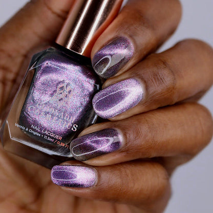 Close-up of nails painted with Lilac Velour Nail Lacquer on deep skin tone. Hand is holding polish bottle.