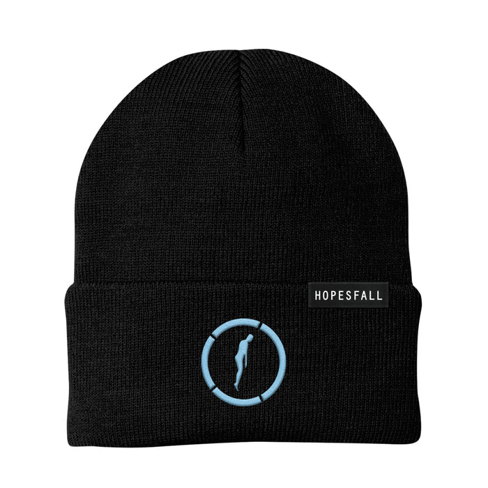 Black beanie with picture of a floating blue silhouette with a circle around it in same blue color. Top right corner of folded section of beanie has a piece of fabric with "HOPESFALL" printed on it.