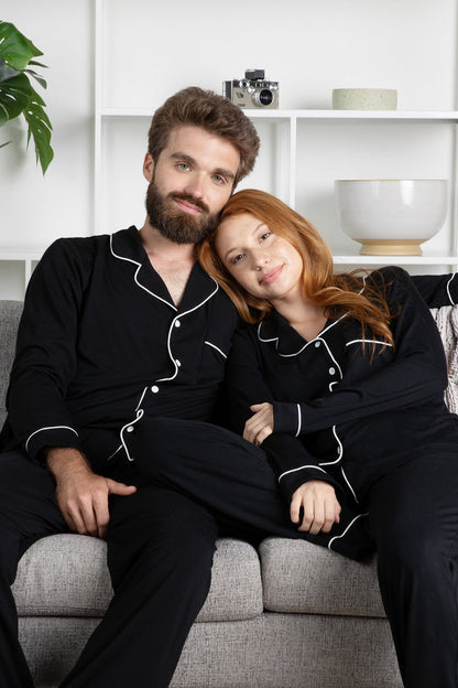 Couple sitting on a couch wearing matching Men's and Women's Long Sleeve Pajama Set in Midnight