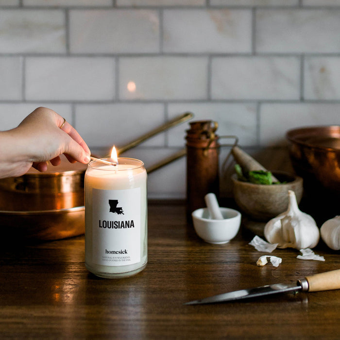 A hand going to lit the Louisiana homesick candle while in the kitchen space.