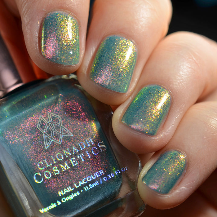 Close-up of nails painted with Love Letter Nail Lacquer on fair skin tone. Hand is holding polish bottle.