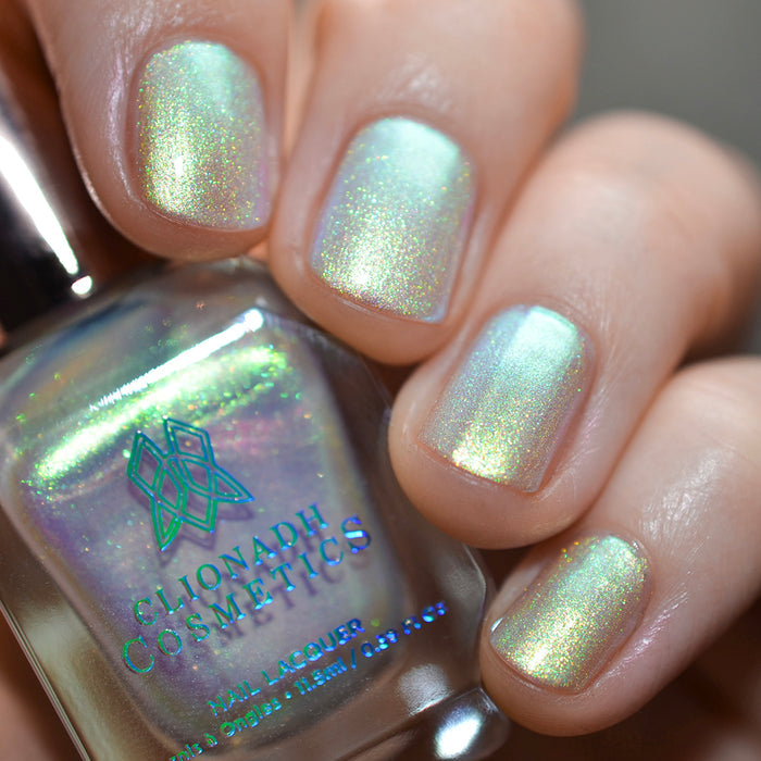 Close-up of nails painted with Lucidum Nail Lacquer on fair skin tone. Hand is holding polish bottle.