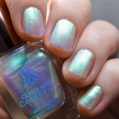 Close-up of nails painted with Lucidum Nail Lacquer on fair skin tone. Hand is holding polish bottle.