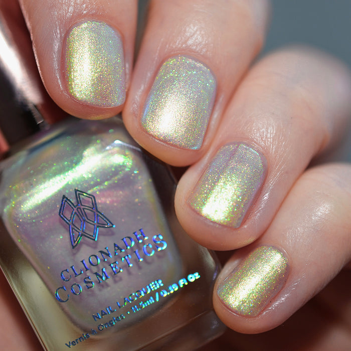 Close-up of nails painted with Lucidum Nail Lacquer on fair skin tone. Hand is holding polish bottle.