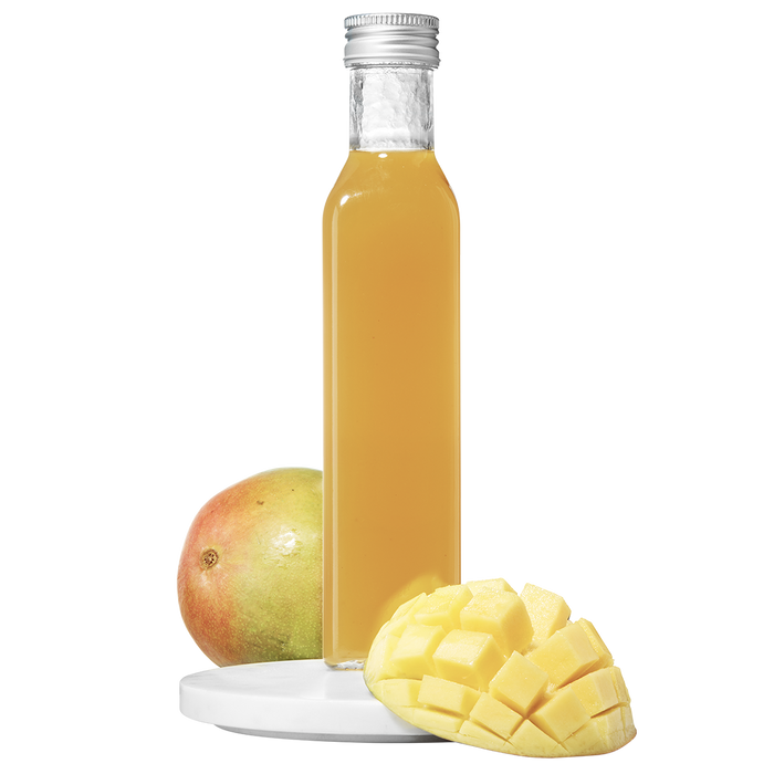 A clear bottle of mango pulp vinegar with a cap, accompanied by a fresh mango cut into slices.