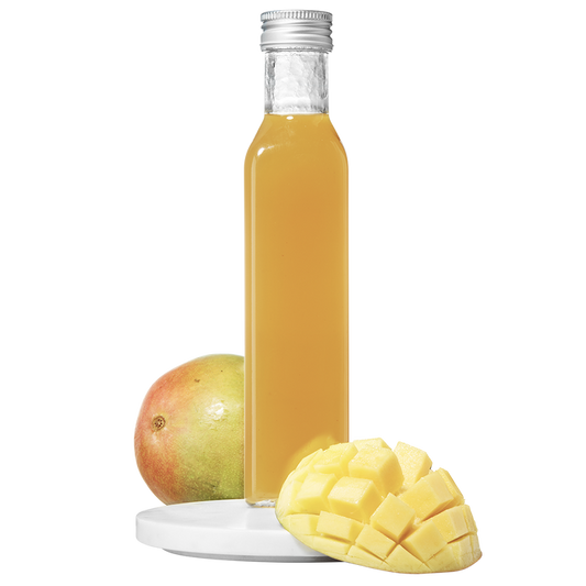 A clear bottle of mango pulp vinegar with a cap, accompanied by a fresh mango cut into slices.