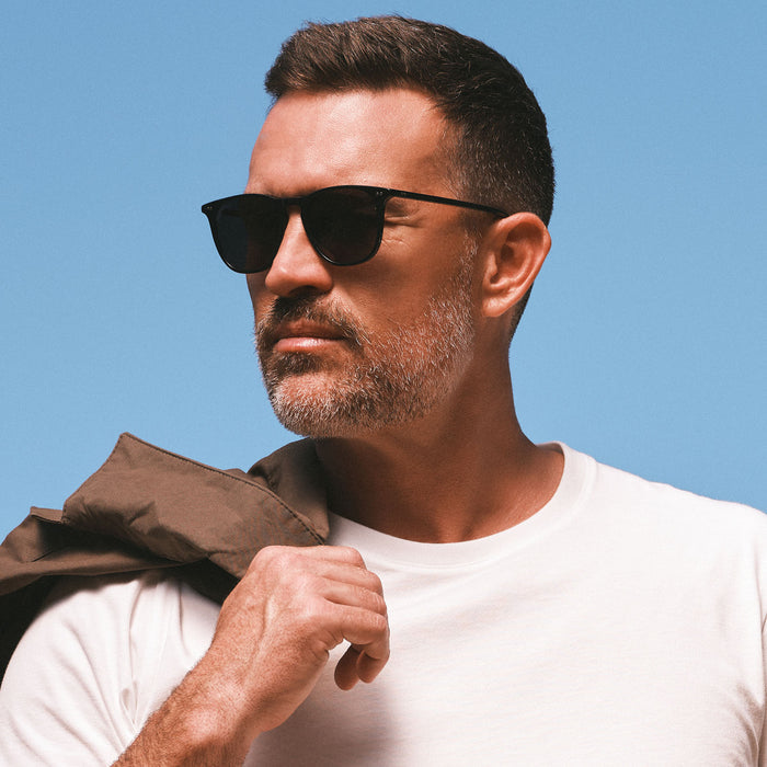 lifestyle - on male model wearing diff eyewear maxwell extra large square sunglasses in a black frame and solid grey polarized lens angled view