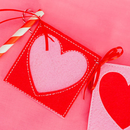 Heart-shaped gift tag with a straw on a pink background