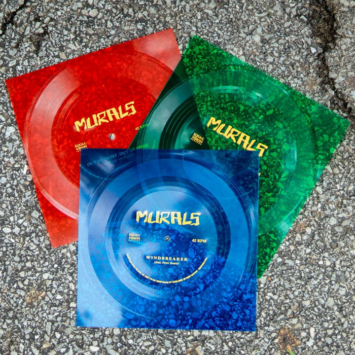 Three translucent flexi vinyl records—red, green, and blue—by Murals are shown in square sleeves with yellow Murals text, displayed on asphalt.