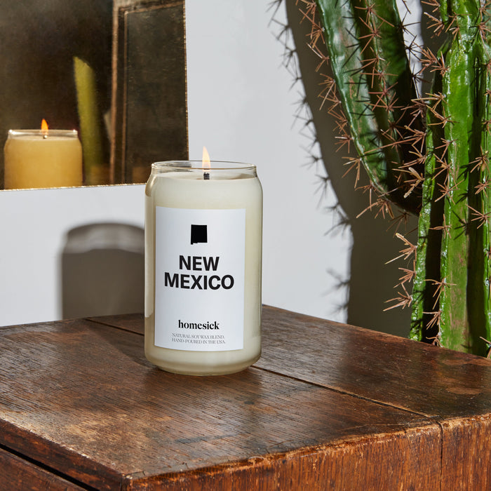 A close up of a dark rustic wood table that has the New Mexico candle on top.