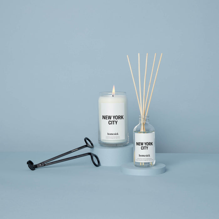 Lit New York City Candle placed next to a New York City diffuser along with a wick trimmer.
