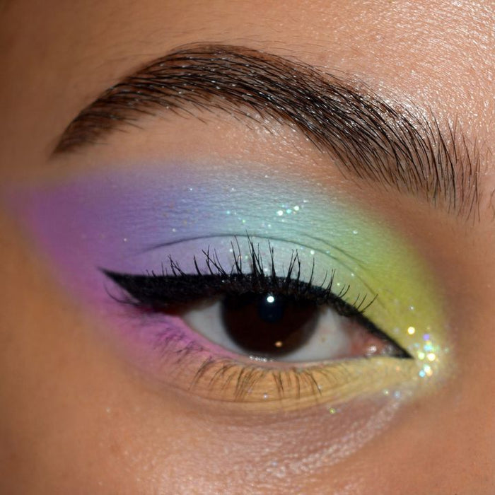 ColourPop BFF Liquid Liner in Numero Uno draws a crisp black wing along the upper lash line, defining a brown eye over pastel shimmer shadow in lavender, sky blue, mint, and lemon with inner-corner sparkle and a groomed brow.