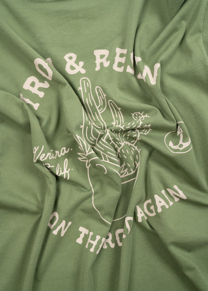 Green shirt with white cactus design and text reading "Iron & Resin, Ventura, Calif, On the Road Again" in a casual style.