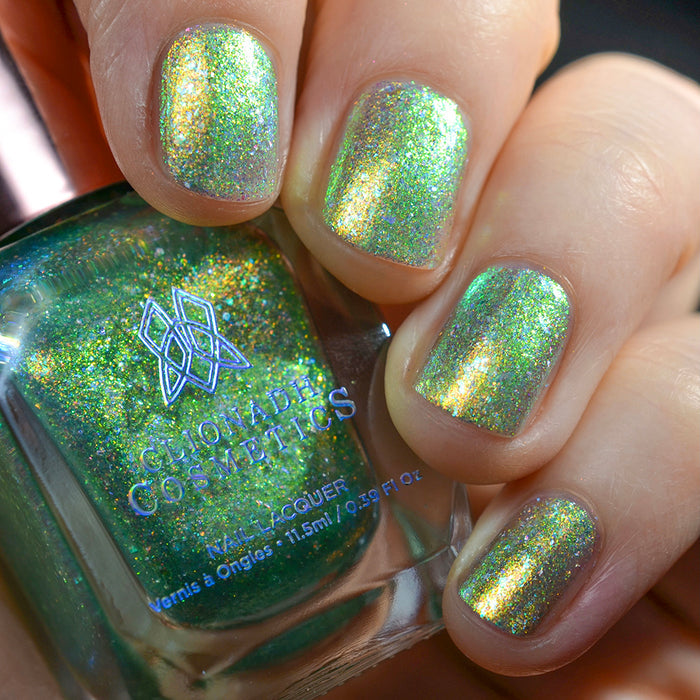 Close-up of nails painted with Ophelia Nail Lacquer on fair skin tone. Hand is holing polish bottle.