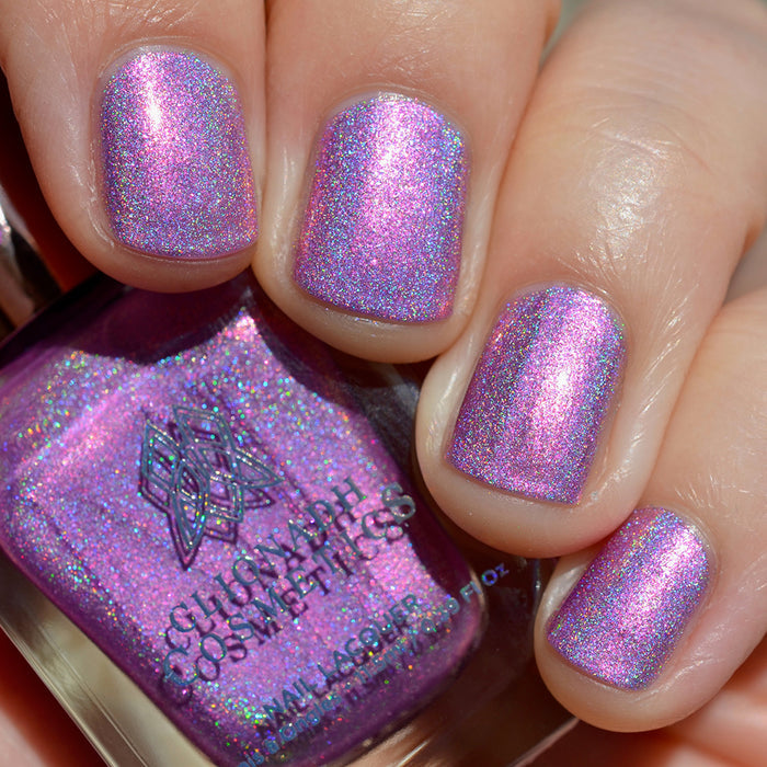 Close-up of nails painted with P.B. & Holo Nail Lacquer on fair skin tone. Hand is holding polish bottle.