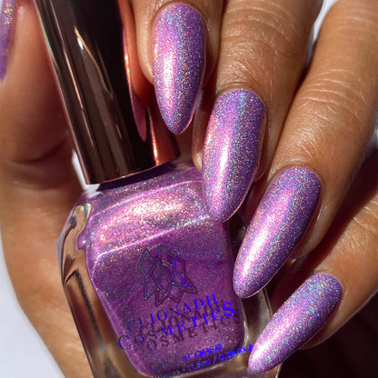 Close-up of nails painted with P.B. & Holo Nail Lacquer on medium skin tone. Hand is holding polish bottle.