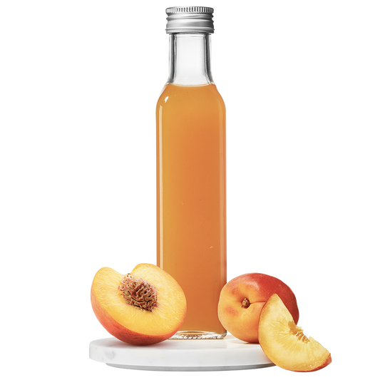 A bottle of Peach Apricot Pulp Vinegar with a peach and a slice of apricot in front of it.