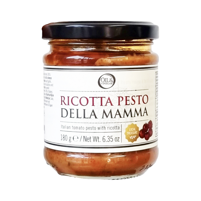 A jar of Pesto della Mamma Ricotta, showing a clear glass jar with the pesto inside and a black lid. The label includes the product name and a brief description.