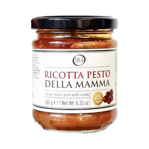A jar of Pesto della Mamma Ricotta, showing a clear glass jar with the pesto inside and a black lid. The label includes the product name and a brief description.