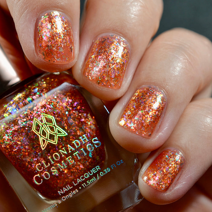 Close-up of nails painted with Autumn Acres Nail Lacquer on fair skin tone. Hand is holding polish bottle.