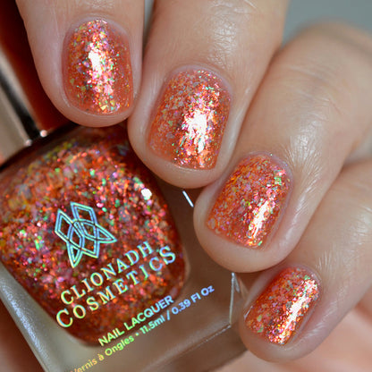 Close-up of nails painted with Autumn Acres Nail Lacquer on fair skin tone. Hand is holding polish bottle.