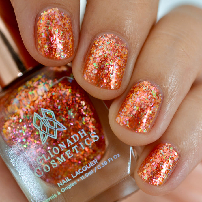 Close-up of nails painted with Autumn Acres Nail Lacquer on fair skin tone. Hand is holding polish bottle.