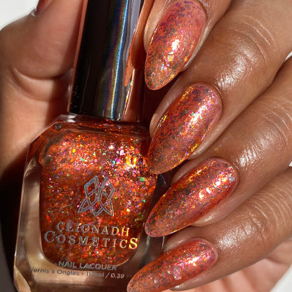 Close-up of nails painted with Autumn Acres Nail Lacquer on medium skin tone. Hand is holding polish bottle.