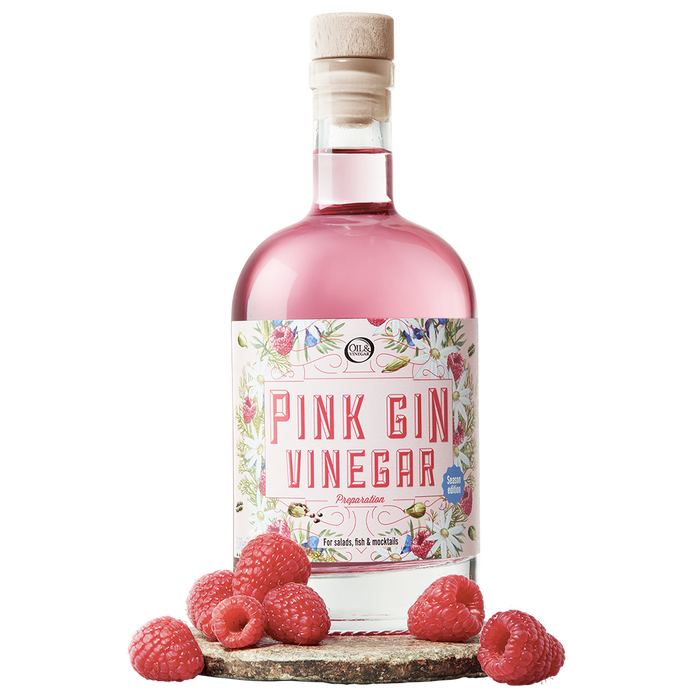 A bottle labeled 'Pink Gin Vinegar' with a pink liquid visible through the clear glass. The bottle is adorned with a label featuring botanical illustrations and has a cork closure.