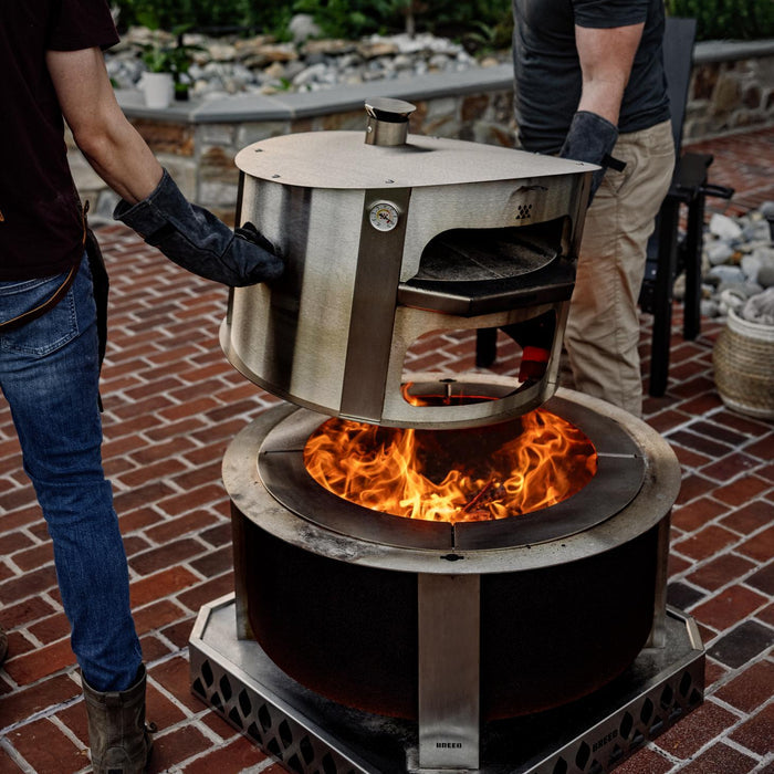 This is an image of two men moving a pizza oven from the firepit