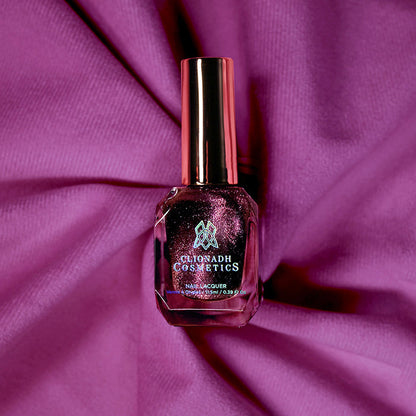 Bottle of nail polish containing Plush Pink on a purple fabric background.