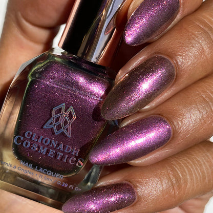 Close-up of nails painted with Plush Pink Nail Lacquer on medium skin tone. Hand is holding polish bottle.