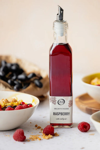 Bottle of raspberry vinegar with a label on a table with berries and yogurt.