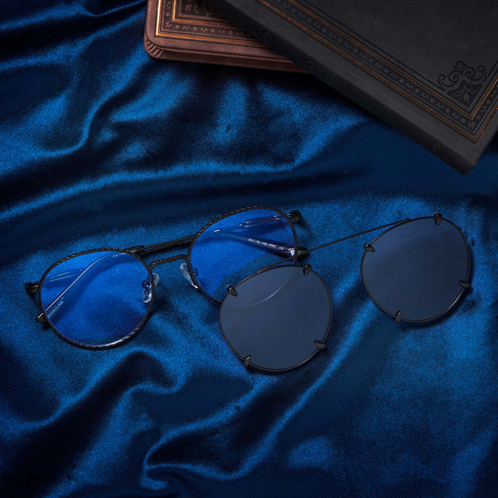Flat-lay of Harry Potter x DIFF Ravenclaw glasses and sunglasses lying folded on top of blue fabric in front of books