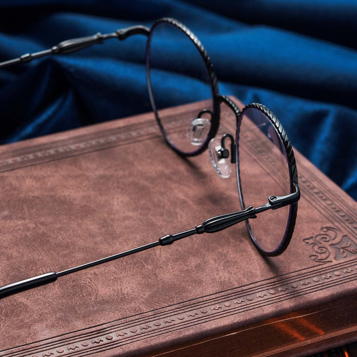 Harry Potter x DIFF Ravenclaw glasses lying open on top of book with blue fabric in the background