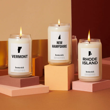 The Vermont, New Hampshire and Rhode Island candles displayed on rectangle and cubed pedestals. The shot is very warm orange and brown.
