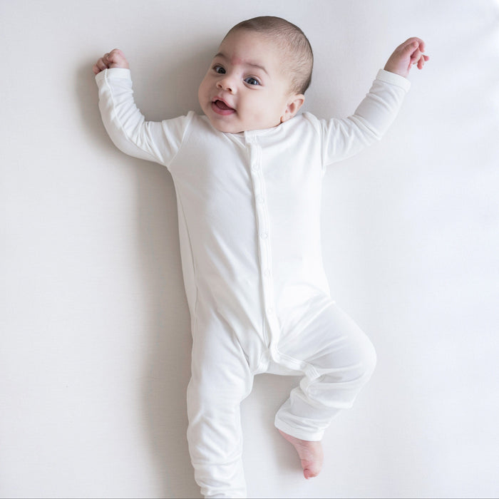Infant laying on white background wearing Kyte Baby Snap Romper Romper in Cloud