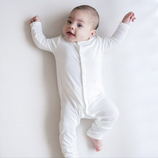 Infant laying on white background wearing Kyte Baby Snap Romper Romper in Cloud