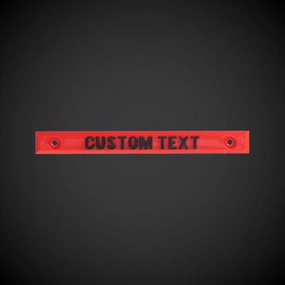 A red custom text screw on label that is designed to be screw on, with text space provided for personalization.