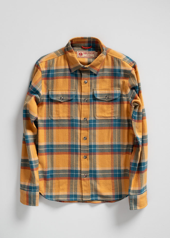 Yellow, blue, and red plaid flannel shirt with buttoned front and chest pockets, displayed on a white background.