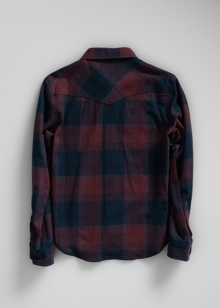 Back view of a long-sleeve, red and blue plaid flannel shirt on a plain background, showcasing its casual style and pattern.