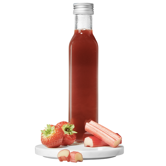 A clear bottle containing red strawberry rhubarb pulp vinegar, with a silver cap, accompanied by fresh strawberries and rhubarb pieces to the side.