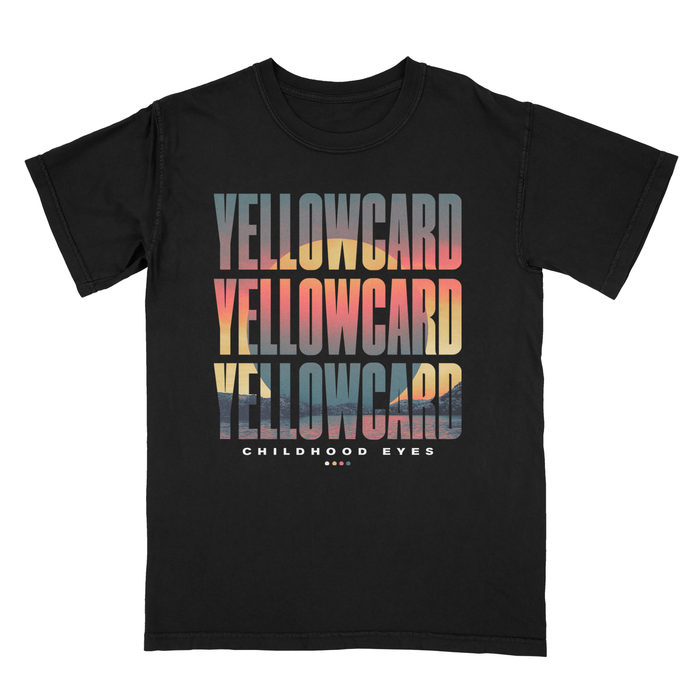 Black t-shirt with the name "Yellowcard" three times. Amidst the words, there is a picture of a sun setting over a lake in the colors grey, red, and yellow. Below the words, it reads "Childhood Eyes" with yellow, orange, red, and grey dots below.