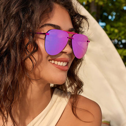 lifestyle - female smiling wearing diff eyewear tahoe aviator sunglasses with a pink rush metallic frame and pink rush mirror lenses angled view